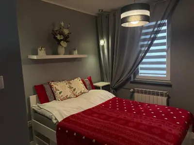 a bedroom with a bed with a red blanket and a window at Ekskluzywny Apartament Joanna w centrum Bochni in Bochnia