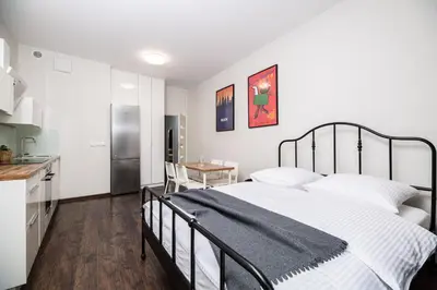 a bedroom with a large bed and a kitchen at Native Apartments Lubelska 14 in Kraków