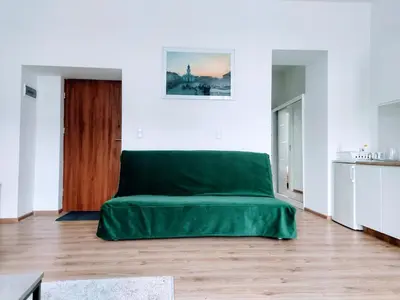 a green couch in a white room with a wooden floor at Apartament Mickiewicza in Wadowice