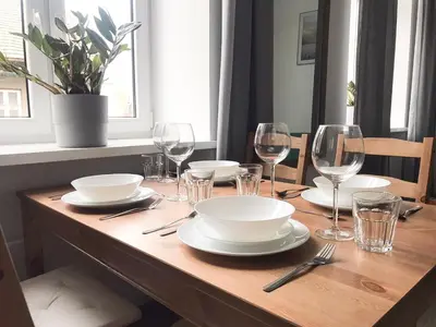 a wooden table with plates and wine glasses on it at Apartament Mickiewicza in Wadowice