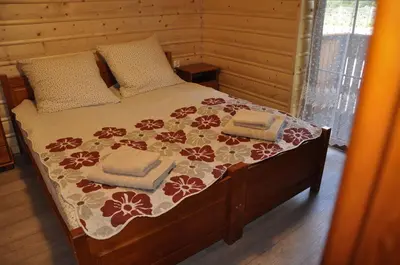 a bed in a wooden room with two towels on it at Willa Wiktoria in Zawoja