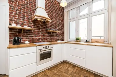 a kitchen with white cabinets and a brick wall at Native Apartments Batorego 7- Bardzo ciche i spokojne miejsce in Kraków