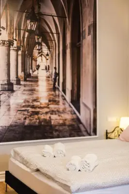 a bedroom with a painting of a hallway with towels on a bed at Vintage Podzamcze Apartment in Kraków