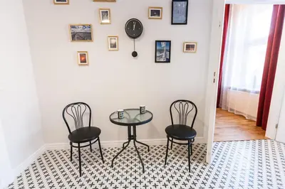 a table with two chairs and a clock on a wall at Vintage Podzamcze Apartment in Kraków