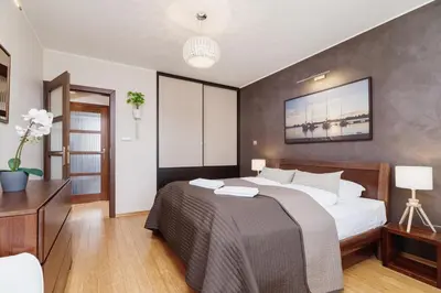 a bedroom with a large white bed and a table at Apartments Obopólna Cracow by Noclegi Renters in Kraków