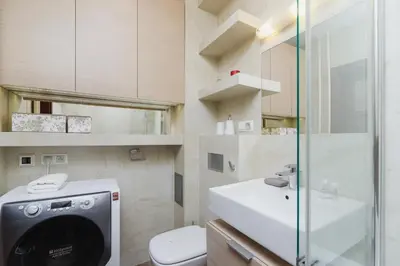 a bathroom with a sink and a washing machine at Apartments Obopólna Cracow by Noclegi Renters in Kraków