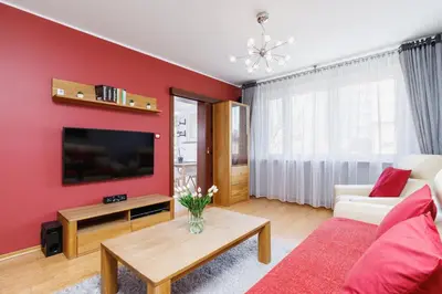 a living room with a red wall at Apartments Obopólna Cracow by Noclegi Renters in Kraków