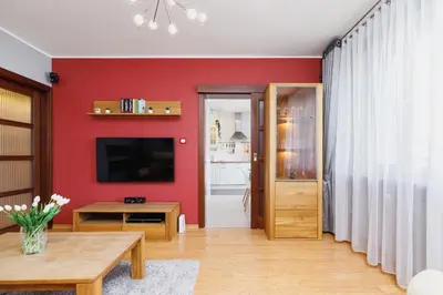 a living room with a red wall at Apartments Obopólna Cracow by Noclegi Renters in Kraków