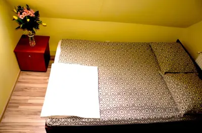 a bed in a room with a vase of flowers on a table at Ośrodek Wypoczynkowo-Szkoleniowy HALNY in Zawoja