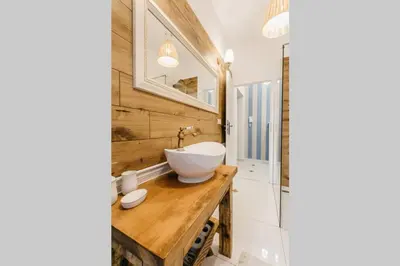 a bathroom with a white bowl sink on a wooden counter at Old Town Apartment DeLux Kraków in Kraków