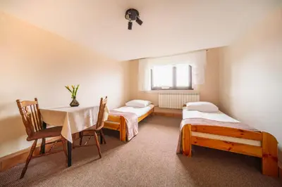 a room with two beds and a table and chairs at Dom na Turystycznej in PyzÃ³wka