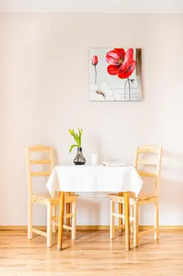 a dining room table with two chairs and a painting on the wall at Dom na Turystycznej in PyzÃ³wka