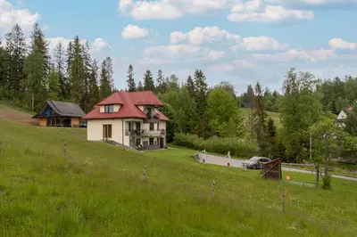 a house with a red roof on a green field at Dom na Turystycznej in PyzÃ³wka