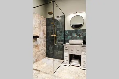 a bathroom with a sink and a shower with a mirror at HOUSEHOST Apartment III: Podbrzezie Street in Kraków