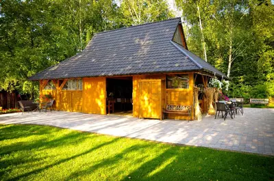 a large wooden cabin with a deck in the grass at Wiśniowy Gaj in Ujanowice