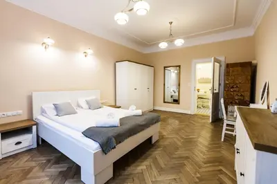 a bedroom with a large white bed and a kitchen at Vintage Poselska Apartment in Kraków