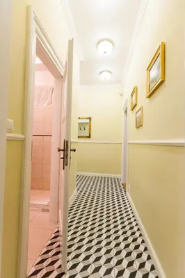 a bathroom with a black and white tiled floor and an open door at Vintage Poselska Apartment in Kraków