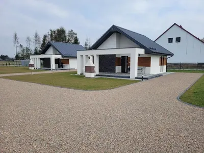 a white house with a black roof and a driveway at APARTAMENTY LAS Zator in Zator