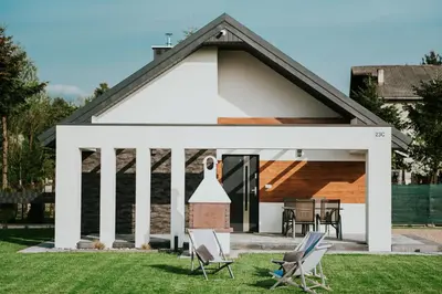 a white house with chairs in the yard at APARTAMENTY LAS Zator in Zator
