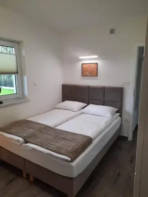 a bedroom with a bed with white sheets and a window at APARTAMENTY LAS Zator in Zator