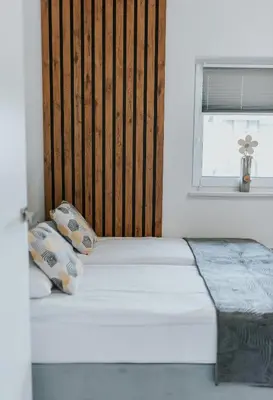 a white bed with two pillows and a window at APARTAMENTY LAS Zator in Zator