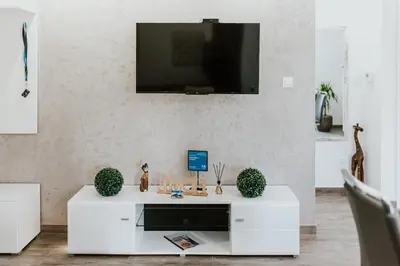 a white living room with a tv on a wall at APARTAMENTY LAS Zator in Zator