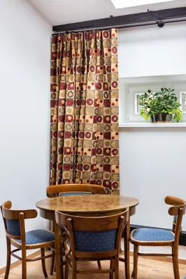 a table and chairs in a room with a curtain at Pałac Zieleniewskich Apartamenty św Marka 31 in Kraków