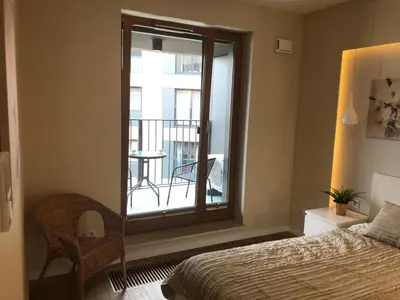 a bedroom with a bed and a window with a balcony at Browar Lubicz by Atrium Apartments in Kraków
