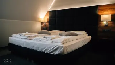 a large bed with white sheets and pillows on it at Hotel Nad Stawem in Skalbmierz