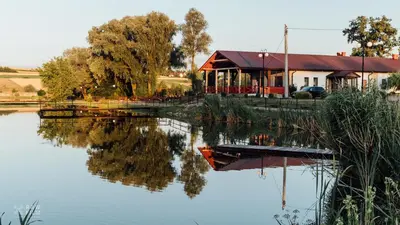a house next to a lake with its reflection in the water at Hotel Nad Stawem in Skalbmierz