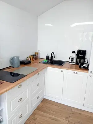 a kitchen with white cabinets and a wooden counter top at Czytelnia w Sadzie in Krzykawka