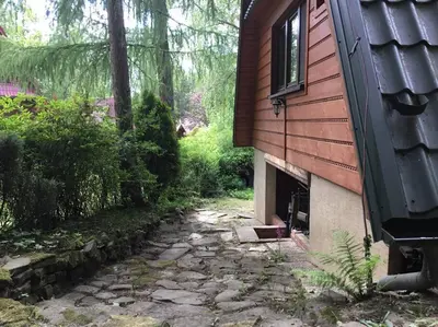 a house with a stone path next to a building at Domek w Lesie in Łęki