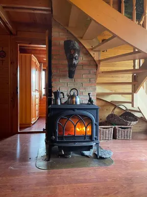 a wood stove in a room with a staircase at Domek w Lesie in Łęki