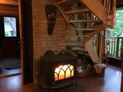 a wood stove in a room with a staircase at Domek w Lesie in Łęki