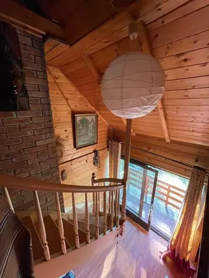 a room with a spiral staircase in a log cabin at Domek w Lesie in Łęki
