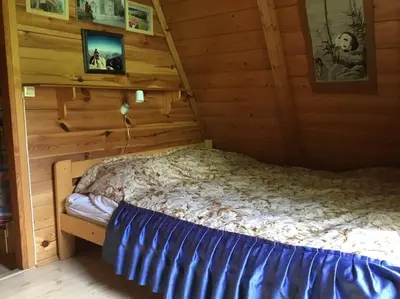 a bed in a room with wooden walls at Domek w Lesie in Łęki