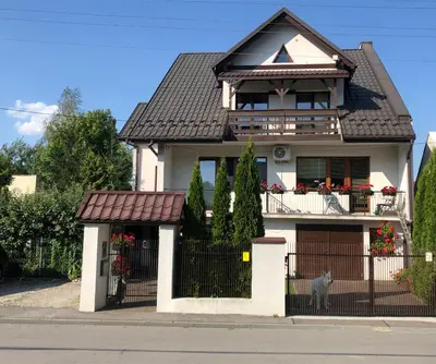 a white house with a fence in front of it at Apartament Bronowice in Kraków