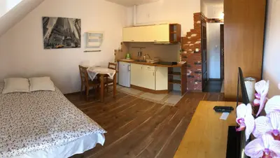 a bedroom with a bed and a kitchen with a table at Apartament Bronowice in Kraków