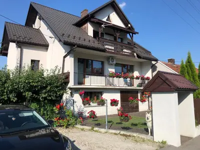 a white house with flowers on the balcony at Apartament Bronowice in Kraków