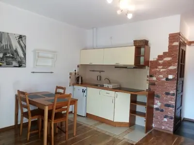 a kitchen with a table and chairs and a brick wall at Apartament Bronowice in Kraków