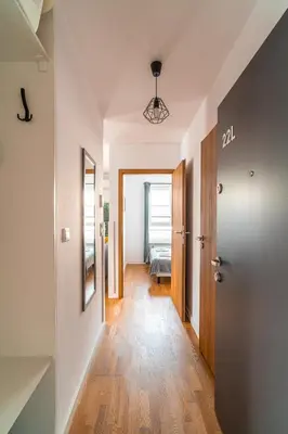 a hallway with white walls and wooden floors and a door at Apartament Chmielna Loft in Kraków