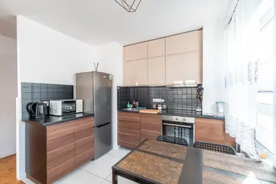 a kitchen with a stainless steel refrigerator and a table at Apartament Chmielna Loft in Kraków