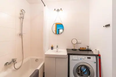 a bathroom with a washing machine and a bath tub at Apartament Chmielna Loft in Kraków