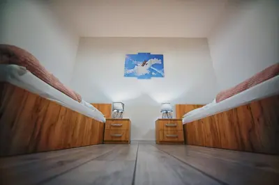 an empty room with two beds and wooden floors at Blue Sky - Apartamenty Premium Zator in Zator