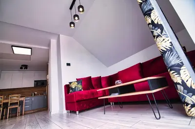 a living room with a red couch and a kitchen at Blue Sky - Apartamenty Premium Zator in Zator