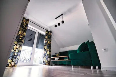 a living room with a green couch and a table at Blue Sky - Apartamenty Premium Zator in Zator