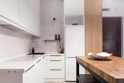 a kitchen with white cabinets and a wooden counter top at WSPANIAŁY, Stylowy Apartament w Sercu Starego Miasta in Kraków