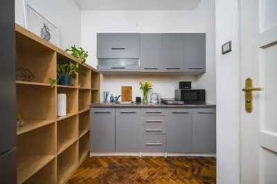 a kitchen with white cabinets and wooden shelves at Krasińskiego Apartments - LOW STANDARD - Riverside & Old Town - by Upstairs in Kraków