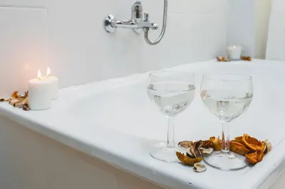 two wine glasses sitting on a counter with a candle at Krasińskiego Apartments - LOW STANDARD - Riverside & Old Town - by Upstairs in Kraków