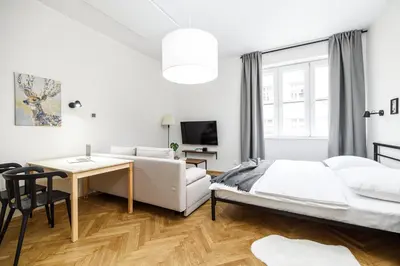 a white bedroom with a bed and a desk at Native Apartments Żuławskiego 8 in Kraków